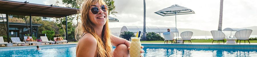 Coral Sea Marina Resort pool with cocktails A woman holding a cocktail overlooking the Coral Sea