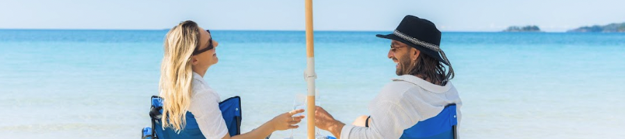 Whitsunday Pearl a couple sitting in camp chairs on the beach holding champagne