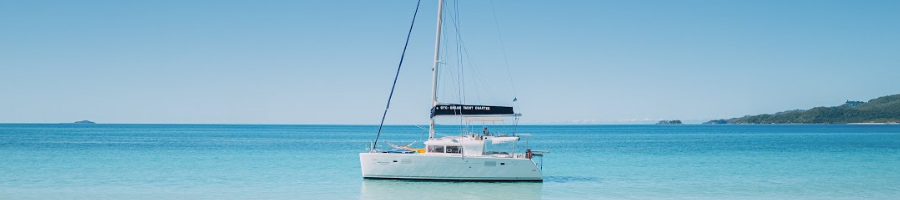 Whitehaven Beach a sailing catamaran sitting offshore of a white sand beach
