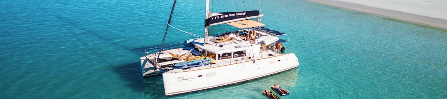 Whitsunday Pearl A sailing catamaran anchored off a white sand beach