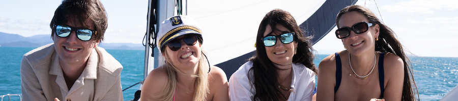 Whitsunday Pearl Four people smiling at the camera while lying on a catamaran