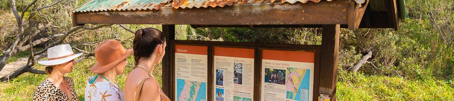 Three girls reading a sign on K'gari (Fraser Island)