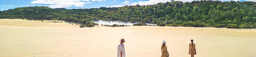 Three women walking along the sand dunes on K'gari