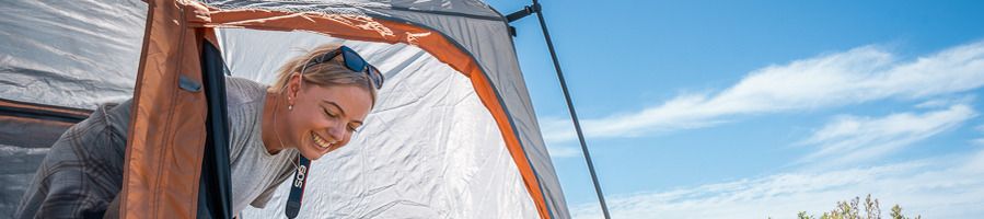 A woman getting out of a tent after a night of camping