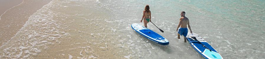 Whitehaven Beach in the Whitsundays A couple pulling stand-up paddleboards along the water