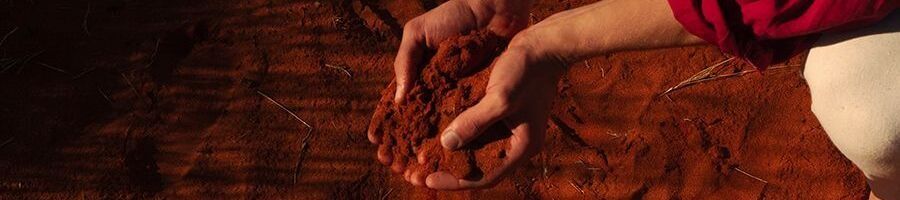 A woman holding the red dirt in the Outback