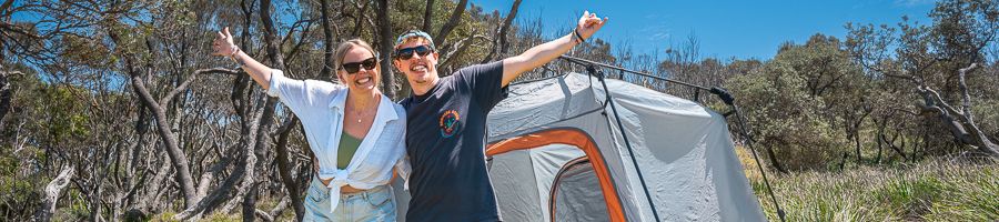 Couple Tent Camping couple smiling in front of tent outside in nature