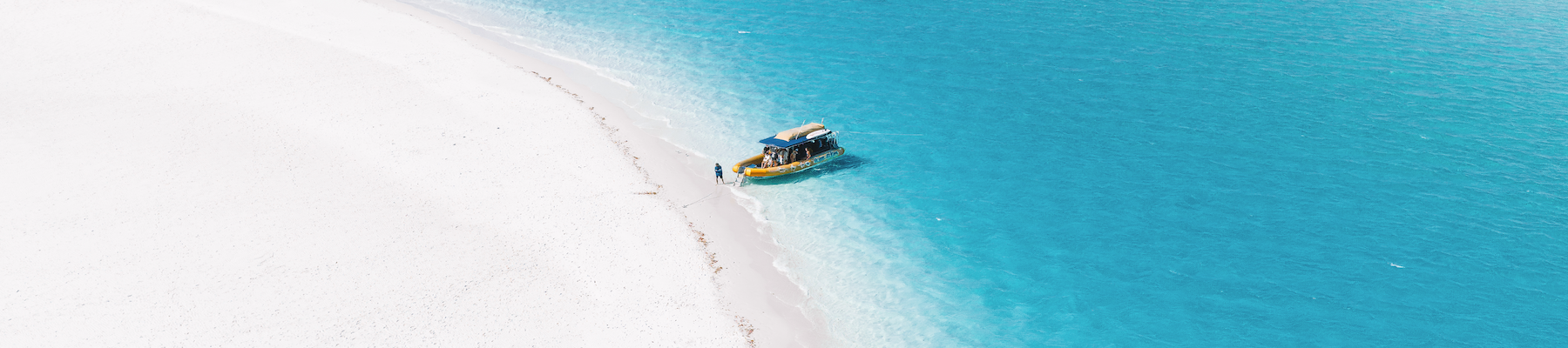 A drone shot of a yellow rafting boat anchored on a beach