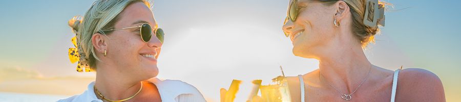 Noosa Boat Hire two girls smiling with drinks on a sunset boat hire cruise