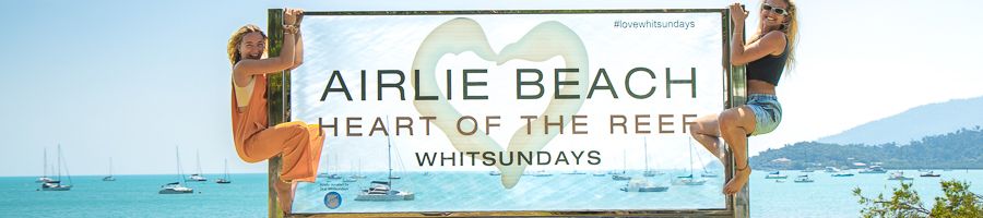 girls posing on the airlie beach downtown sign