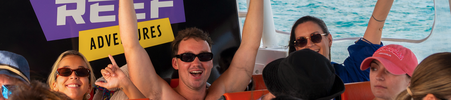 Reef Adventures a group of friends on a boat with their arms up