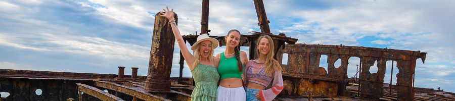 three girls posing in front of maheno shipwreck on kgari