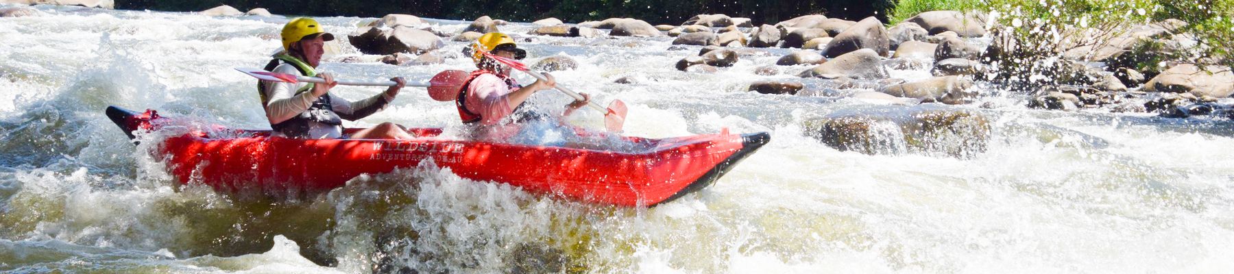 a man and woman in a kayak going down a rapid