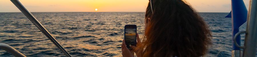 girl taking a photo of the sunset on a whitsundays yacht