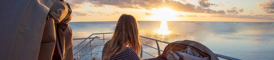 girl watching sunrise over great barrier reef from reefsleep bed