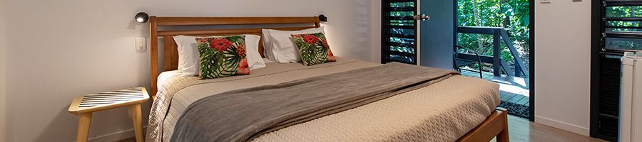 King bed in St Crispin Deluxe Cabin with a made bed, rainforest and private ensuite